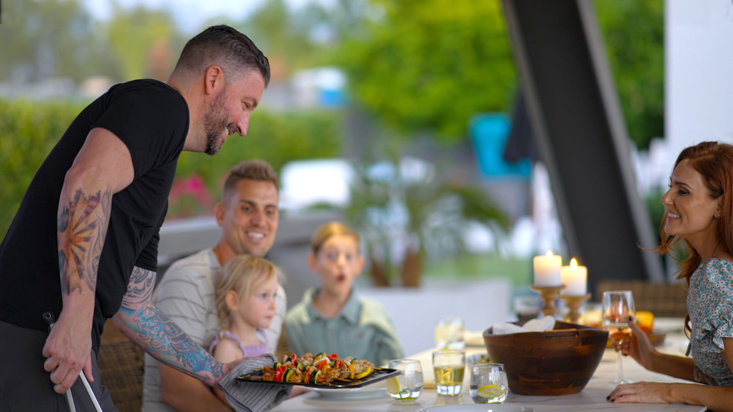 Serving food to a family at an outdoor dining table.