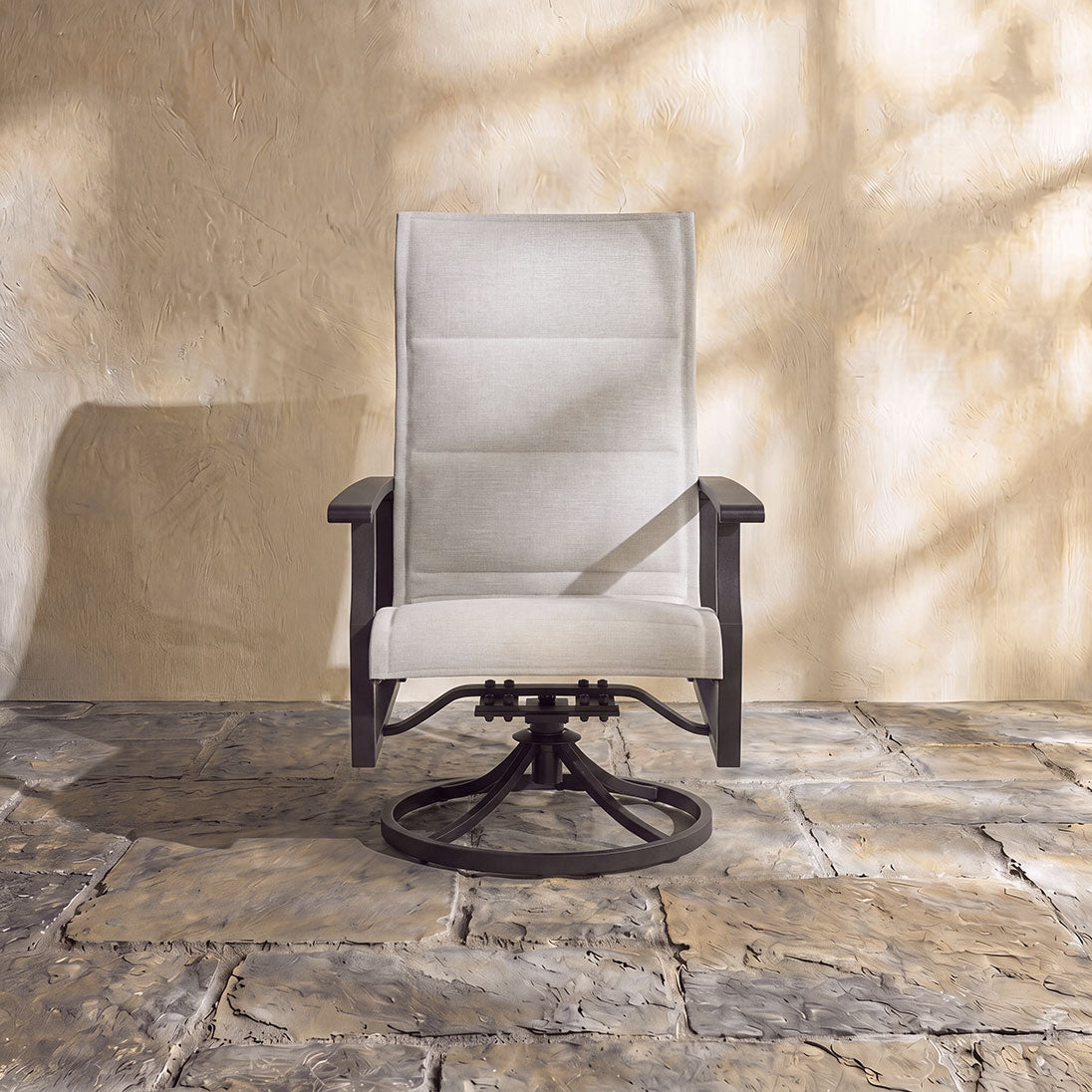 Padded sling swivel chair in light beige featuring a supportive high backrest and a sturdy circular swivel base.