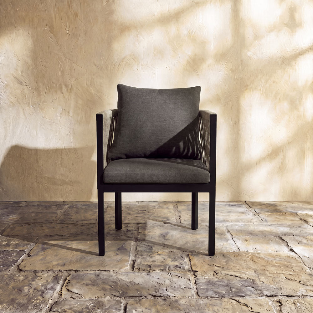 Contemporary patio arm chair with decorative woven side panels and deep-seated charcoal grey cushions.