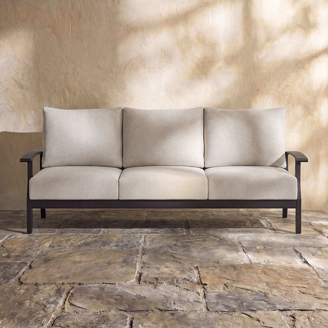 Contemporary outdoor garden sofa with weather-resistant beige upholstery and a minimalist dark frame.