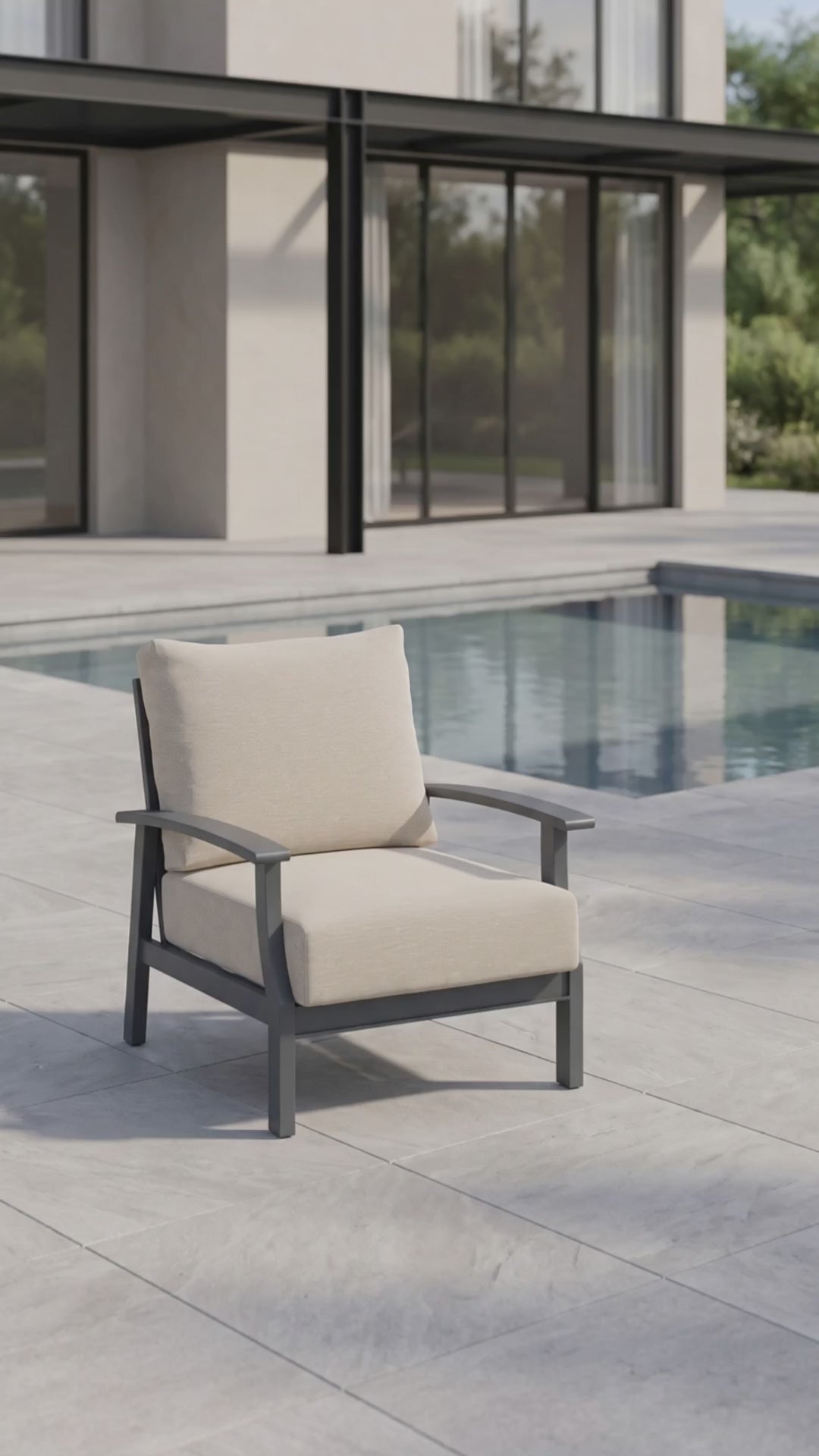 Rockport Club Chair with a black aluminum frame and cream cushions, shown poolside on a modern patio.