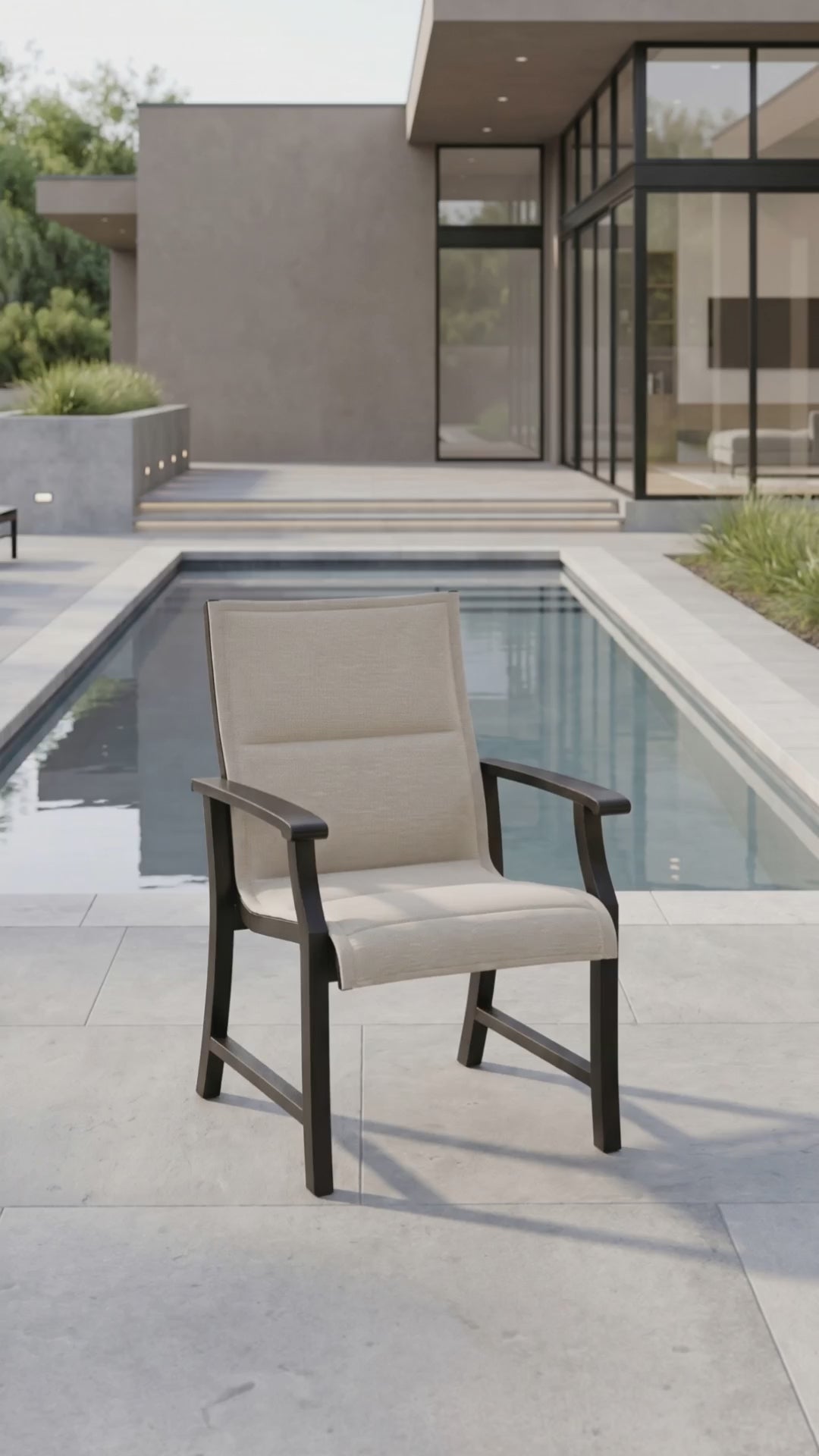 Outdoor dining chair with a padded oatmeal sling seat and back, ombre aluminum frame, shown on a modern poolside patio.